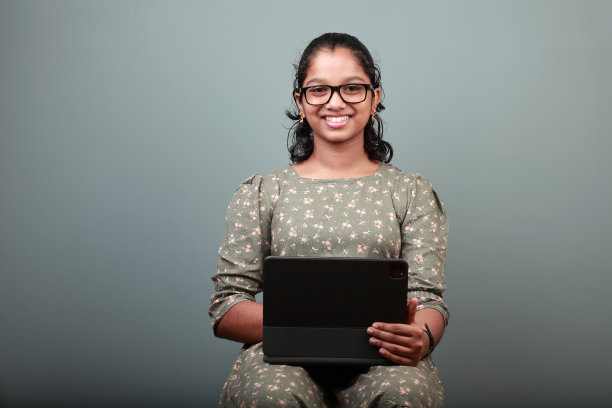 一个微笑的印度女孩手里拿着平板手机图片下载