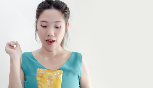 亚洲美女都抱着薯片包，满心欢喜地吃着。图片下载