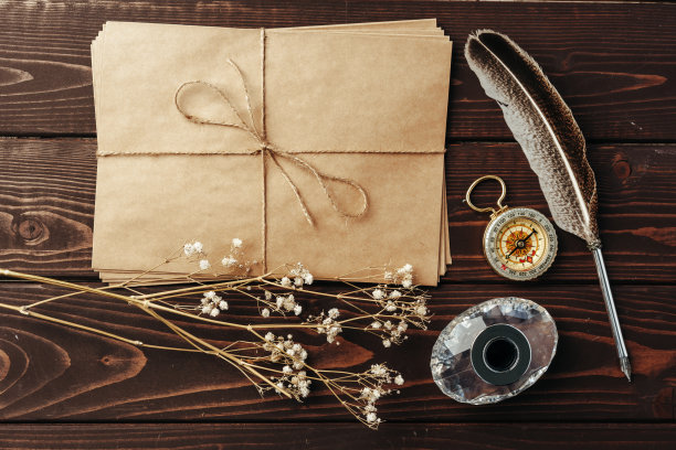 一张旧纸的顶视图，棕色的木质纹理背景与羽毛图片下载