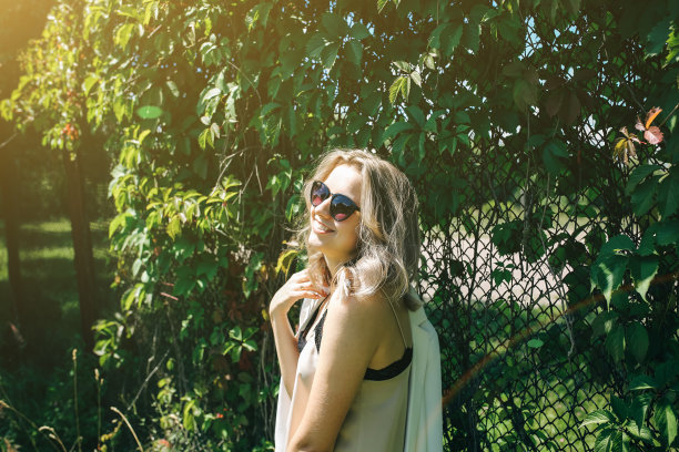 时髦的时髦女孩站在户外常春藤叶墙附近。为年轻女性拍摄时尚照片。金色短发，戴着酷酷的眼镜。夏日生活写真。图片下载