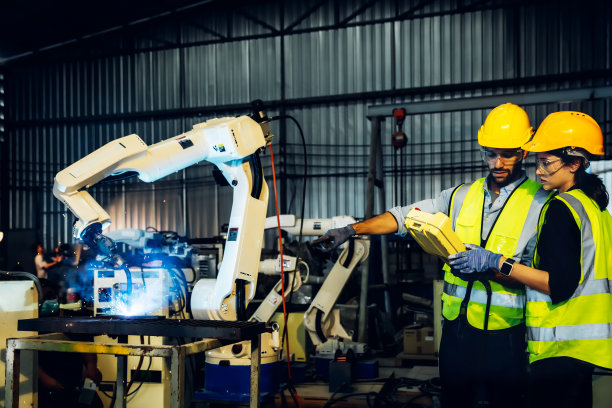 智能工厂的工程师或工人。在工业智能工厂中，工程师检查和控制自动化机械臂图片下载