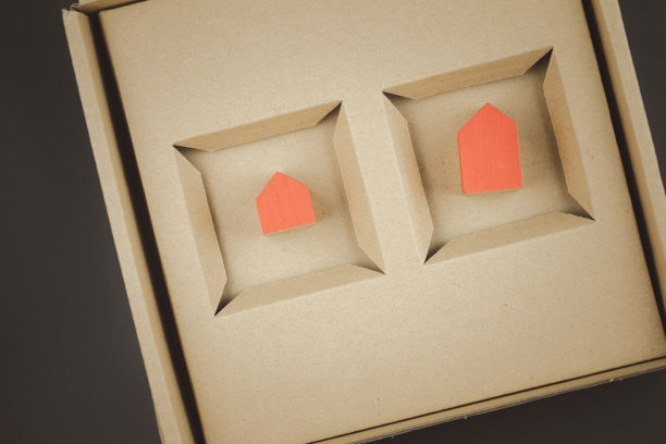 两个红色的微型房子在一个棕色的盒子里。作为礼物的住房。出售不动产。图片下载