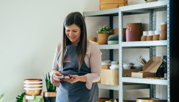 穿着围裙的快乐女陶工在她的工作室里制作零浪费的粘土圣诞饰品图片下载