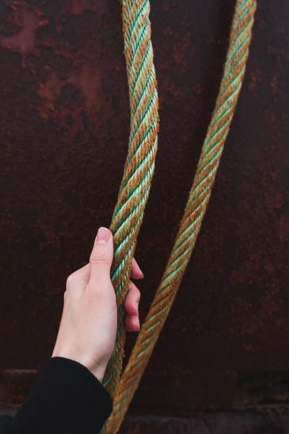 一个女人的手握着一艘生锈船的绳子图片下载