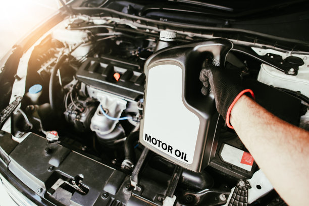 机械师在汽车发动机舱里拿着一瓶发动机油的手图片下载