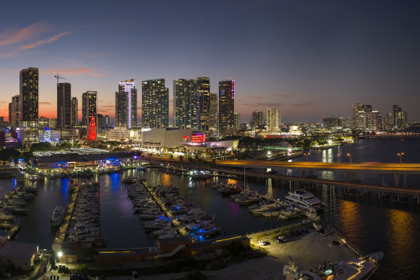 航拍的游艇在迈阿密码头的海湾市场与比斯坎湾的水和布里克尔的摩天大楼，城市的金融中心在夜晚的倒影图片下载
