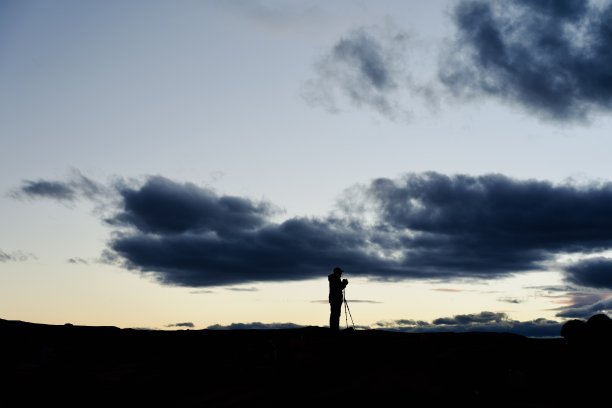 多云天空下日落时的摄影师剪影图片下载
