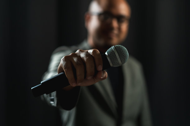 在公司商业活动中，自信成功的演说家在舞台上讲话，聚光灯照亮了黑暗。在会议大厅演讲的公众演说家。喜剧演员。图片下载