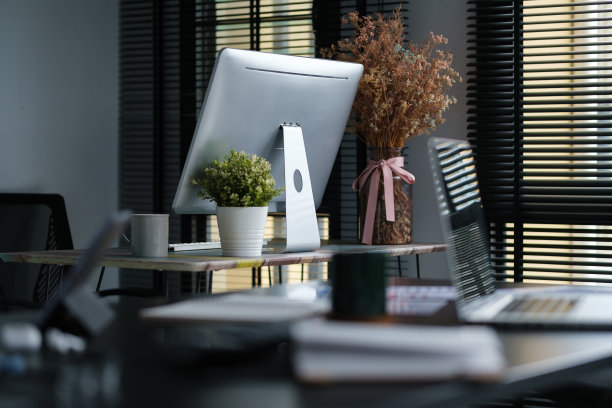 舒适的办公室内，电脑显示器，书籍，室内植物和文具在桌子上。图片下载