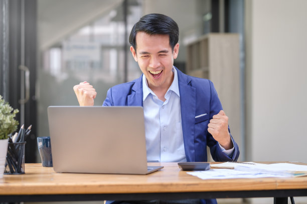 快乐的商人在笔记本电脑上阅读好消息，庆祝商业成功。图片下载