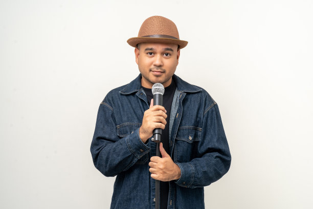 快乐年轻的亚洲男人唱的歌。孤立背景的艺术家兼歌手。自信的人在演播室拿着麦克风公开演讲。图片下载