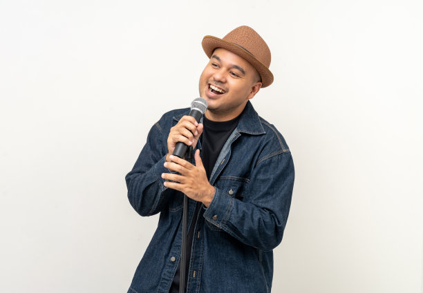 快乐年轻的亚洲男人唱的歌。孤立背景的艺术家兼歌手。自信的人在演播室拿着麦克风公开演讲。图片下载