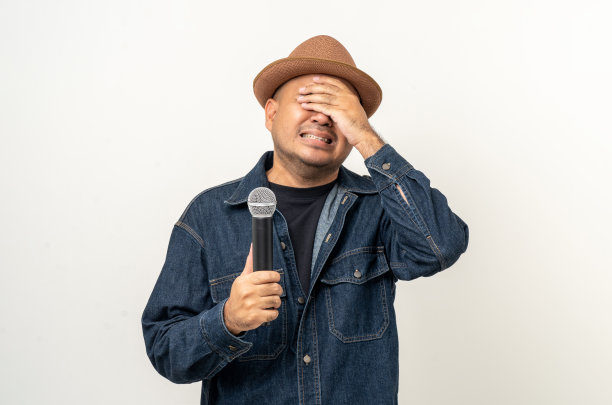 震惊的脸年轻的亚洲男子唱歌。孤立背景的艺术家兼歌手。自信的人在演播室拿着麦克风公开演讲。图片下载