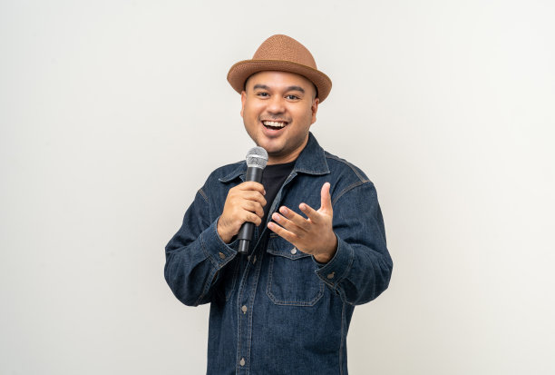 快乐年轻的亚洲男人唱的歌。孤立背景的艺术家兼歌手。自信的人在演播室拿着麦克风公开演讲。图片下载