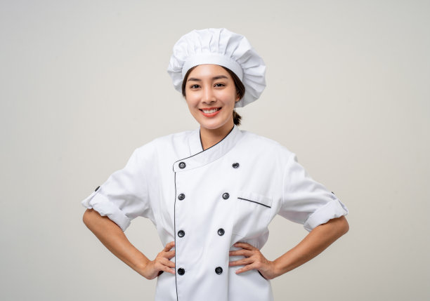 微笑的年轻美丽的亚洲女厨师，穿着制服，在孤立的背景下摆姿势。女厨师职业厨师或面包师在厨房餐厅和酒店工作。图片下载