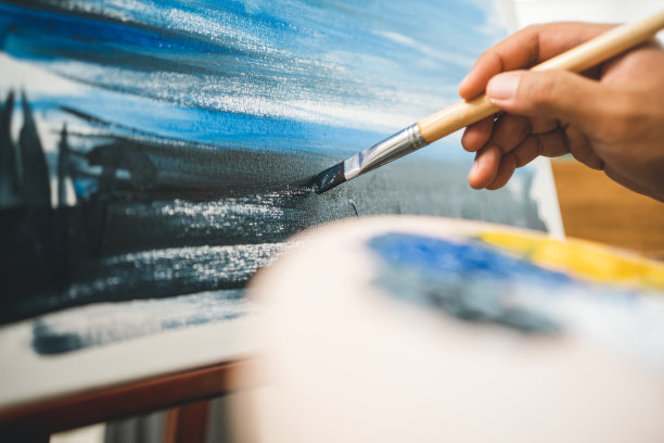 亚洲男艺术家正在用画笔和不同的丙烯酸颜料作画。作为艺术概念的男艺术家在创意工作室的画布上作画图片下载