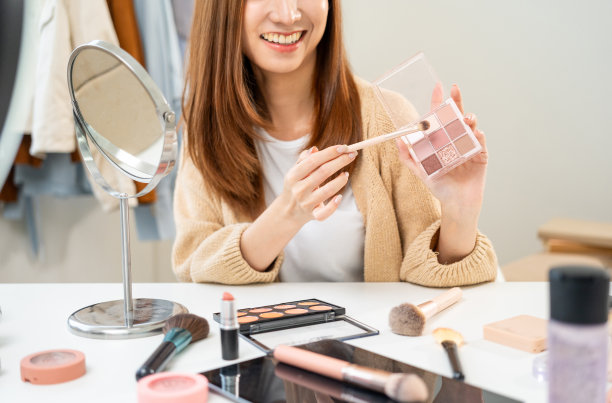 年轻美丽的亚洲女性视频博主直播化妆化妆教程内容与眼影。网红们在社交媒体上用各种化妆品录制视频，专业化妆图片下载