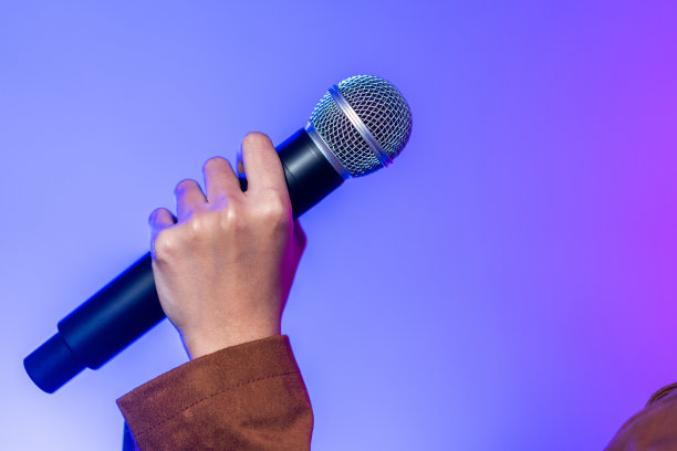 迷人的女歌手在舞台上演唱音乐，聚光灯穿过音乐会的黑暗。音乐家在大厅里用霓虹灯现场表演。图片下载