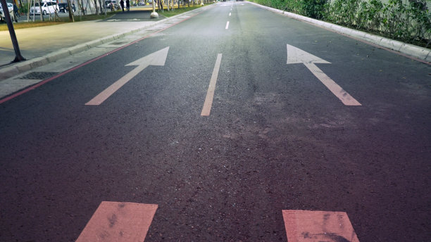 路上有两个白色的箭头。柏油路上的箭头标志。图片下载