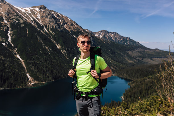男人的男性肖像，在山中旅行。穿着绿色运动服在户外徒步旅行的人。真实人物的生活方式摄影，智能手表的旅游理念。他戴着墨镜，背着双肩包。图片下载