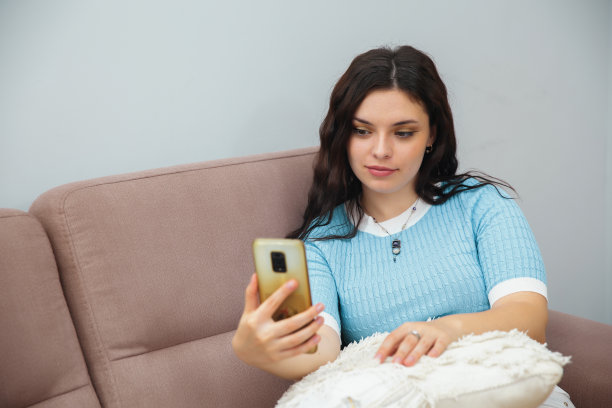 一个女人坐在沙发上，用手机自拍图片下载