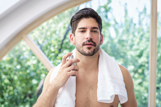 一个满脸胡茬的帅哥站在浴室里往脸上喷古龙水图片下载