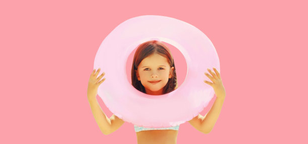 夏季肖像的小女孩游泳充气环孤立在粉红色的背景图片下载