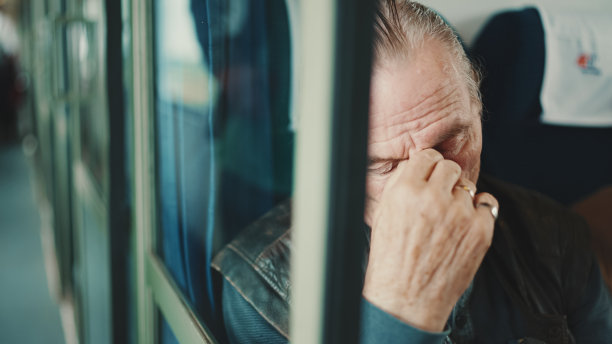 老人坐在火车上用手按摩眼睛的照片图片下载