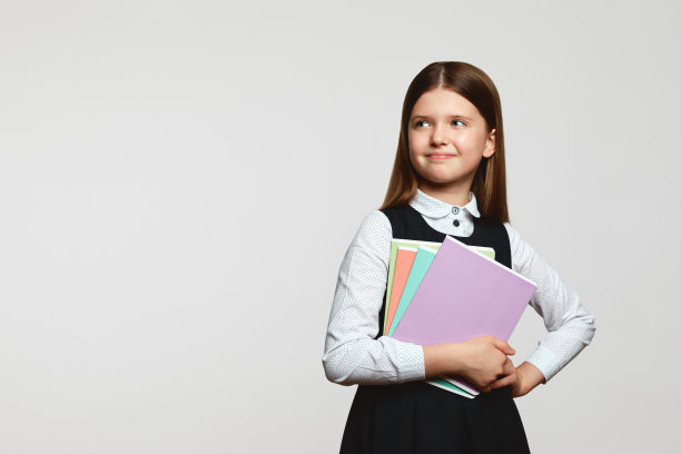可爱的小女孩穿着校服，拿着课本，看着自由的空间图片下载