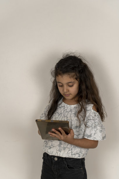 小女孩在白色背景前使用平板电脑。图片下载