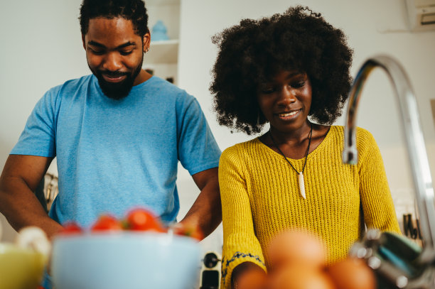 一对幸福的异族夫妇正在家里的厨房里做家务和做饭。图片下载