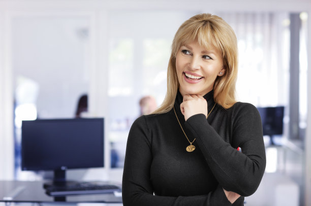 身穿黑色毛衣的金发女商人站在办公室的特写图片下载