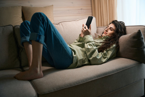 快乐的女士在家里拿着智能手机查看社交媒体图片下载