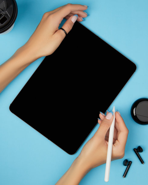 平躺俯视图女人的手拿着数字平板电脑与蓝色背景的空白屏幕。家庭办公空间图片下载