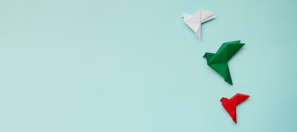 三只折纸鸽子，红，白，绿在光的背景上图片下载