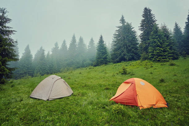 夏天的景色，小舒适的现代旅游帐篷在美丽的蓝天下，在多雾的山上覆盖着森林的背景。图片下载