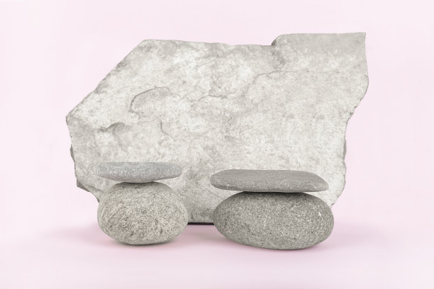 一堆堆的石头和垂直站立的石头在淡粉色的背景。图片下载