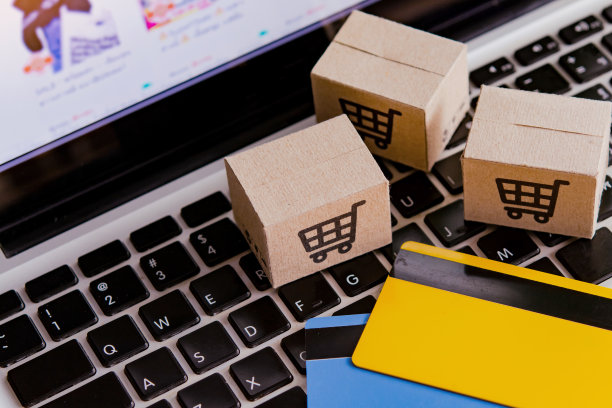 网上购物。信用卡和笔记本电脑键盘上有购物车标志的纸板箱。网上购物服务。提供送货上门服务图片下载