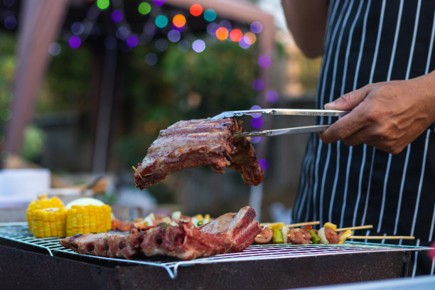 烧烤聚会用的肉和串料放在烤架上烤烧烤，为今晚家人参加烧烤聚会做好准备。派对背景图片有文本的复制空间。图片下载