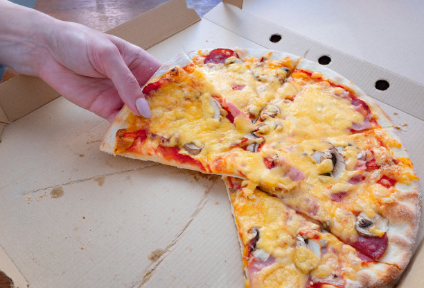 女人的手从纸盒里拿着一片美味的披萨图片下载