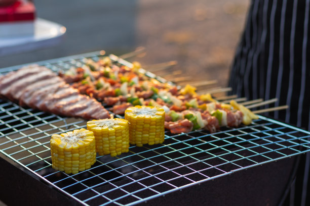 烧烤聚会用的肉和串料放在烤架上烤烧烤，为今晚家人参加烧烤聚会做好准备。派对背景图片有文本的复制空间。图片下载