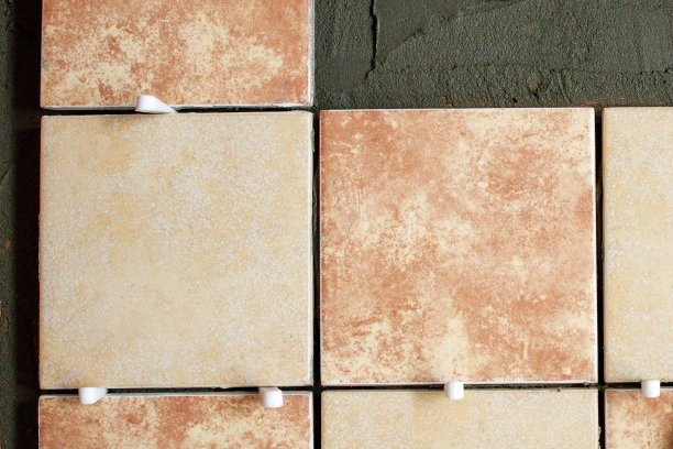 墙上新铺的棕色和奶油色瓷砖，上面有塑料垫圈。维修工作图片下载