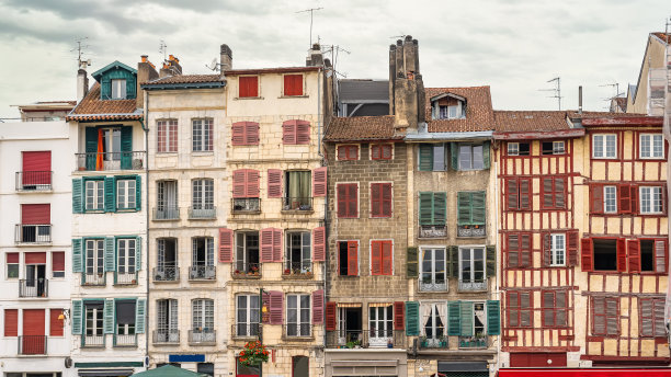 典型的巴约讷老房子，狭窄的建筑上有彩色的窗户，法国。图片下载