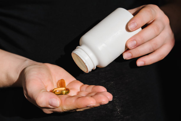孕妇手持欧米茄3。女孩每天服用维生素。特写照片的女性手拿补品或维生素与一个白色的瓶子。放文字的地方。妊娠、治疗、医药保健理念图片下载