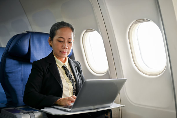 一位严肃的资深亚洲女商人在飞机上用笔记本电脑管理她的工作图片下载
