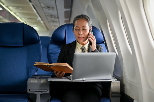 一位专业而忙碌的资深亚洲女商人在飞机上打电话图片下载