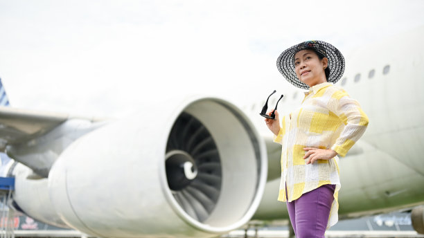 一位身着夏装的迷人的亚洲高级女士站在机场。暑假概念图片下载