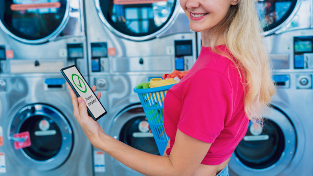 年轻女子用手机和银行应用程序支付洗衣费图片下载
