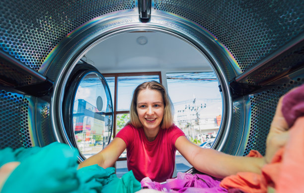 年轻漂亮的女人在洗衣房洗衣服和烘干衣服图片下载
