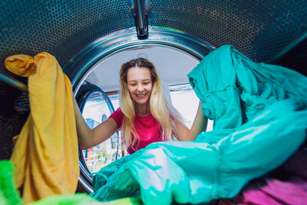年轻漂亮的女人在洗衣房洗衣服和烘干衣服图片下载